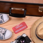 מזוודה, חפצים וכרטיס עליו כתוב ביטוח נסיעות לחו"ל
