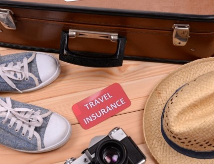 מזוודה, חפצים וכרטיס עליו כתוב ביטוח נסיעות לחו"ל